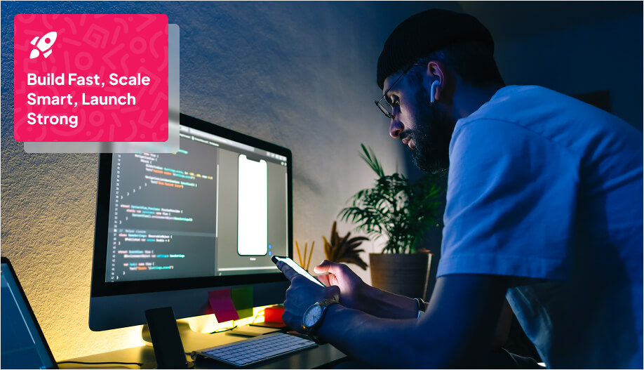 developer with his phone facing a computer that shows a coding program